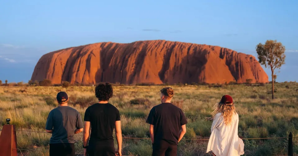 Walkers seen from behind, facing Uluru